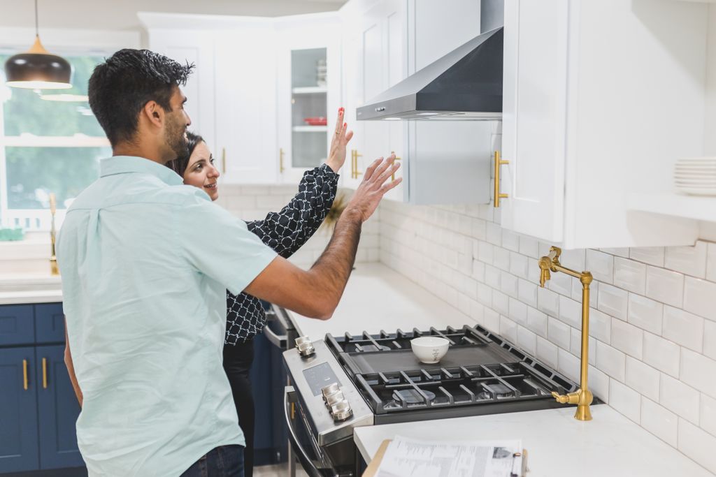 A real estate agent demonstrates kitchen features in a modern home. Ideal for real estate and lifestyle concepts.