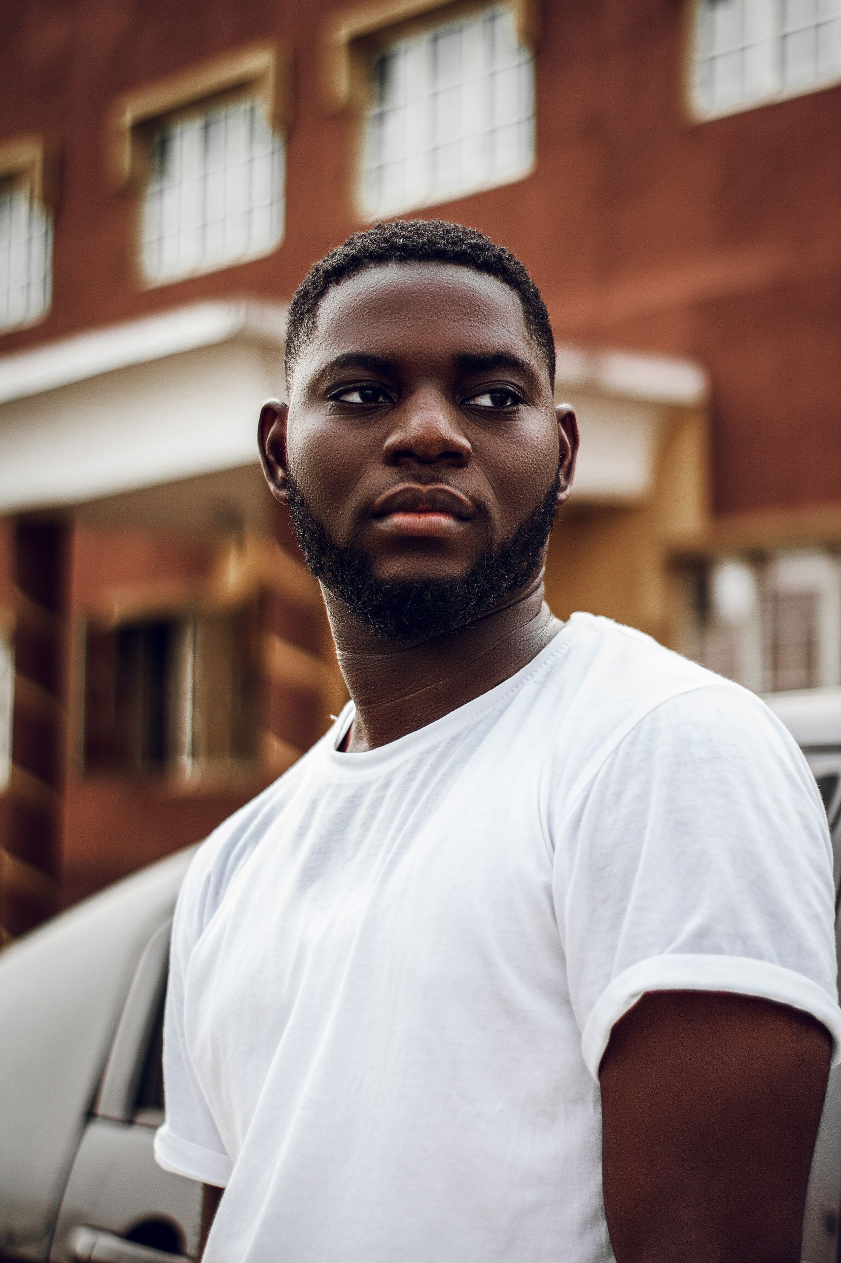 Portrait of a bearded man in white shirt against urban Lagos backdrop.